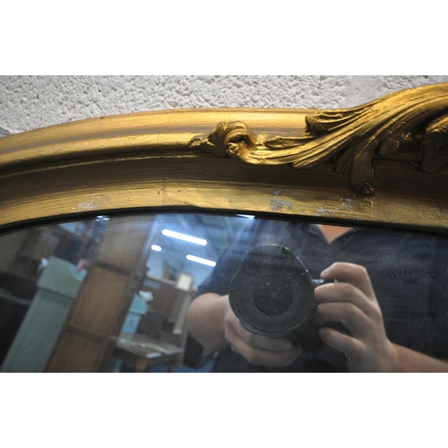 1229 - A LARGE GILT FRAMED ARCHED OVERMANTEL MIRROR, with scrolled crest and side details, width 138cm x de... 