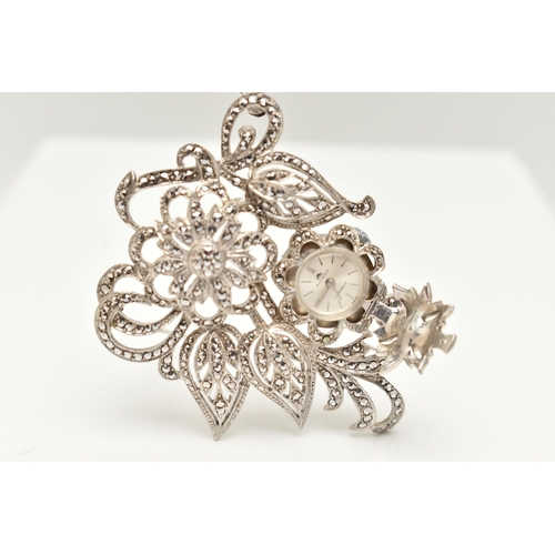 38 - A 'BUCHERER' BROOCH WATCH, a white metal floral brooch set with marcasite, hinged flower lifting to ... 