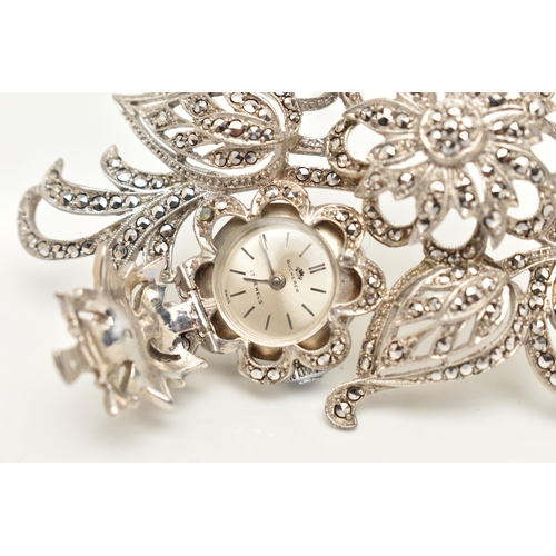 38 - A 'BUCHERER' BROOCH WATCH, a white metal floral brooch set with marcasite, hinged flower lifting to ... 