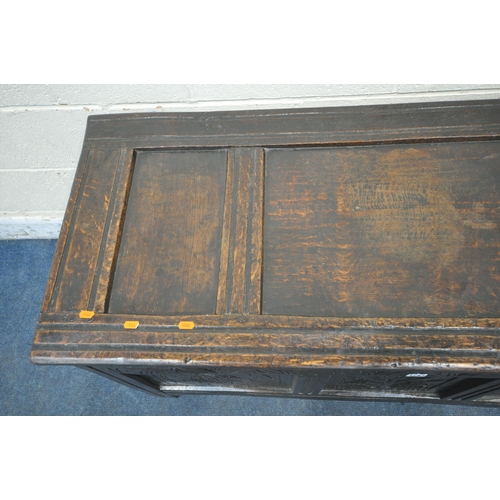 1243 - A GEORGIAN OAK COFFER, the hinged lid enclosing a candle box, the front with three carved panels, wi... 