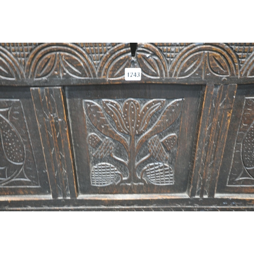 1243 - A GEORGIAN OAK COFFER, the hinged lid enclosing a candle box, the front with three carved panels, wi... 