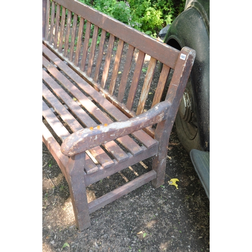 1021 - A MODERN HARDWOOD GARDEN BENCH with carved arm rests, slatted back and seat width 181cm