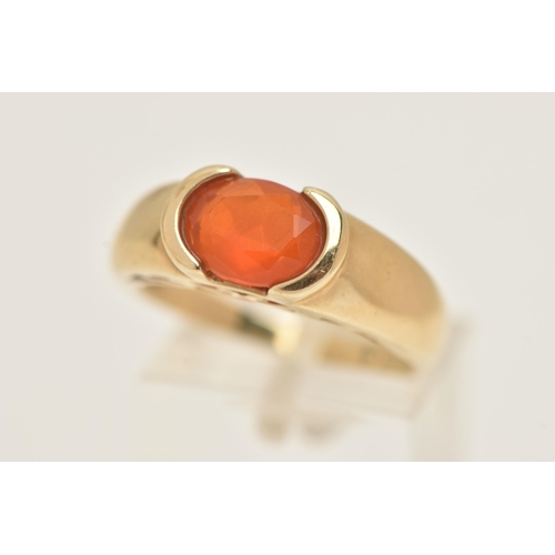 60 - A 9CT GOLD GEM SET RING, an oval cut faceted orange stone, assessed as fire opal, half bezel set in ... 