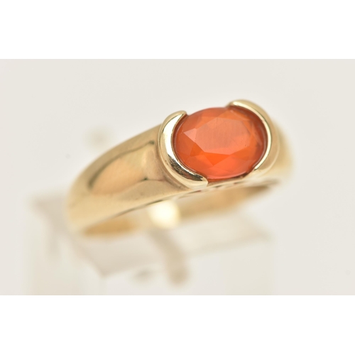 60 - A 9CT GOLD GEM SET RING, an oval cut faceted orange stone, assessed as fire opal, half bezel set in ... 