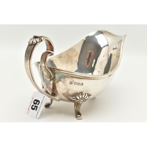 65 - AN ELIZABETH II SILVER GRAVY BOAT, polished form with scroll handle and shell detailed thumb rest, r... 