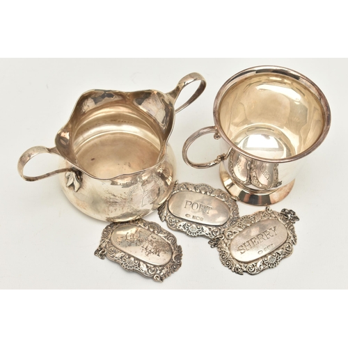 67 - A SILVER SUGAR BOWL, CUP AND THREE DECANTER LABELS, the polished sugar bowl, fitted with double hand... 