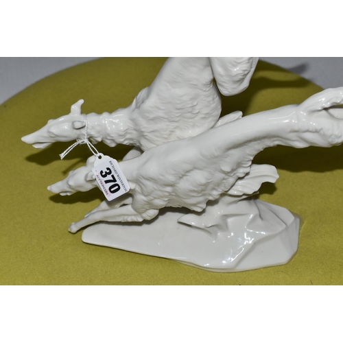 370 - A  HUTSCHENREUTHER WHITE PORCELAIN MODEL OF TWO BORZOI DOGS LEAPING OVER A ROCKY OUTCROP, designed b... 