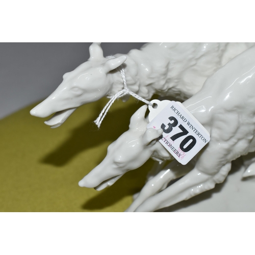 370 - A  HUTSCHENREUTHER WHITE PORCELAIN MODEL OF TWO BORZOI DOGS LEAPING OVER A ROCKY OUTCROP, designed b... 