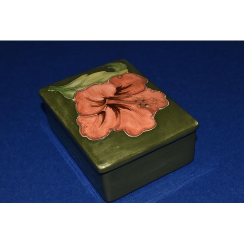 374 - A MOORCROFT POTTERY RECTANGULAR TRINKET BOX AND COVER, decorated in Coral Hibiscus pattern on a gree... 