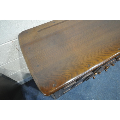 1200 - LUCIAN ERCOLANI, A MID CENTURY ELM AND BEECH SIDEBOARD, fitted four drawers, flanked by two cupboard... 