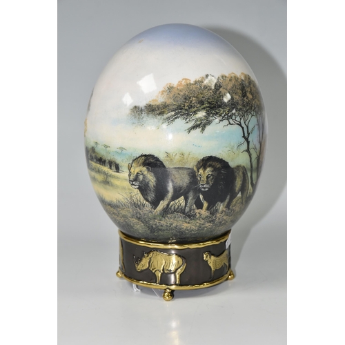 439 - A DECORATED OSTRICH EGG AND STAND, egg is transfer printed and tinted with an African savannah scene... 