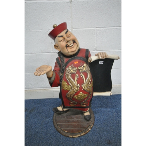 1219 - AN ORIENTAL ADVERTISING STAND, in the form of a man holding a scroll, with hand raised to hold a tra... 