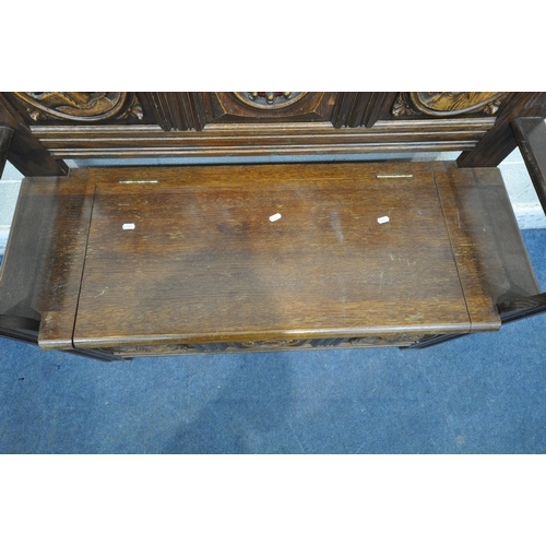 1236 - A 20TH CENTURY OAK MONKS BENCH, with four Romayne style panels, a hinged seat, and open armrests, wi... 