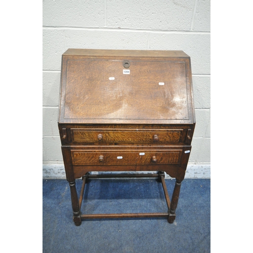 1284 - A 20TH CENTURY OAK BUREAU, the fall front door enclosing a fitted interior, above two drawers, raise... 