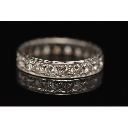 11 - A DIAMOND ETERNITY RING, designed as brilliant cut diamonds in a milligrain border, with engraved de... 