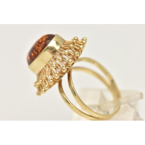 50 - A DRESS RING, designed as a central oval imitation amber cabochon within a collet setting to the wir... 