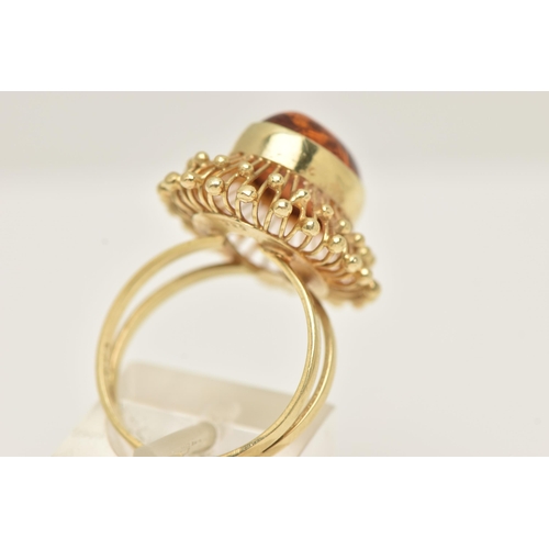 50 - A DRESS RING, designed as a central oval imitation amber cabochon within a collet setting to the wir... 