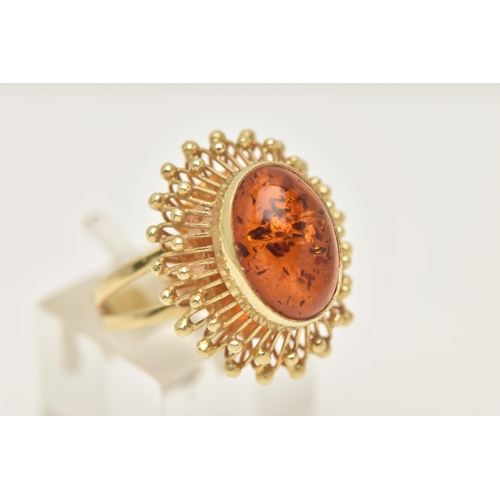 50 - A DRESS RING, designed as a central oval imitation amber cabochon within a collet setting to the wir... 