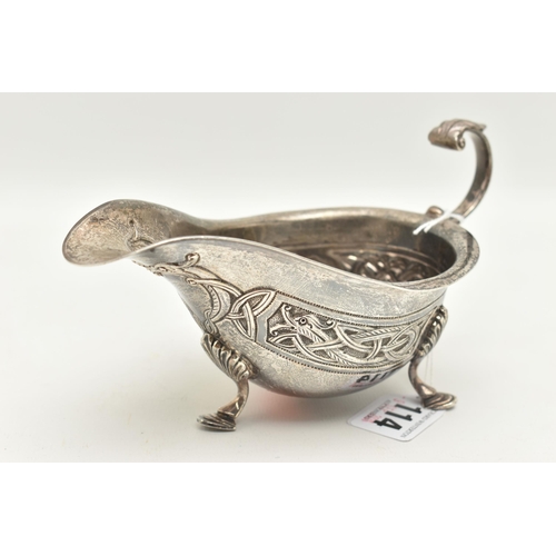 114 - AN IRISH GEORGE V SILVER SAUCE BOAT, with Celtic embossed design, raised on three shell capped feet,... 