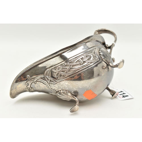 114 - AN IRISH GEORGE V SILVER SAUCE BOAT, with Celtic embossed design, raised on three shell capped feet,... 