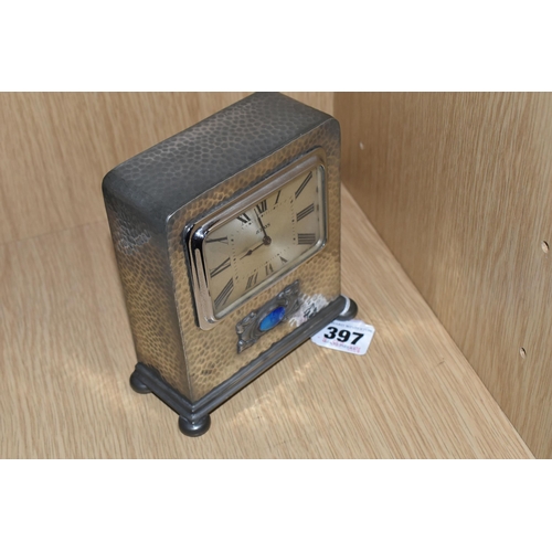 397 - A LIBERTY TUDRIC PEWTER EIGHT DAY MANTEL CLOCK, of rectangular form with hammered finish, raised on ... 