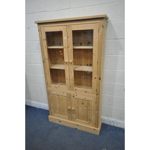 1305 - A MODERN PINE BOOKCASE, fitted with double glazed doors, above double cupboard doors, width 101cm x ... 