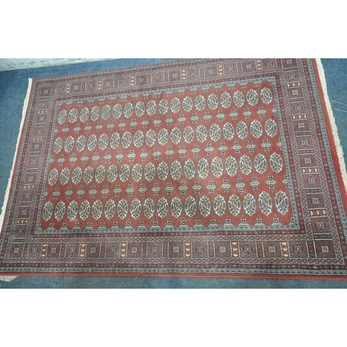 1308 - A RED GROUND HAND FINISHED TURKISH HALI BUHARA RUG, with seventy- two medallions, and a multi-strap ... 