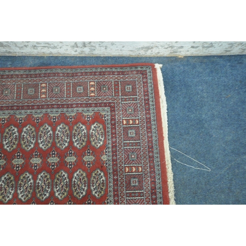 1308 - A RED GROUND HAND FINISHED TURKISH HALI BUHARA RUG, with seventy- two medallions, and a multi-strap ... 