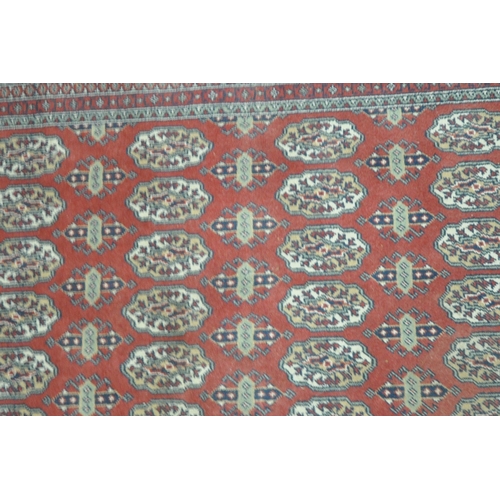 1308 - A RED GROUND HAND FINISHED TURKISH HALI BUHARA RUG, with seventy- two medallions, and a multi-strap ... 