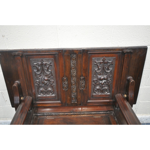 1315 - A 20TH CENTURY MAHOGANY MONKS BENCH, the tilting backrest with carved foliate details, that rest on ... 