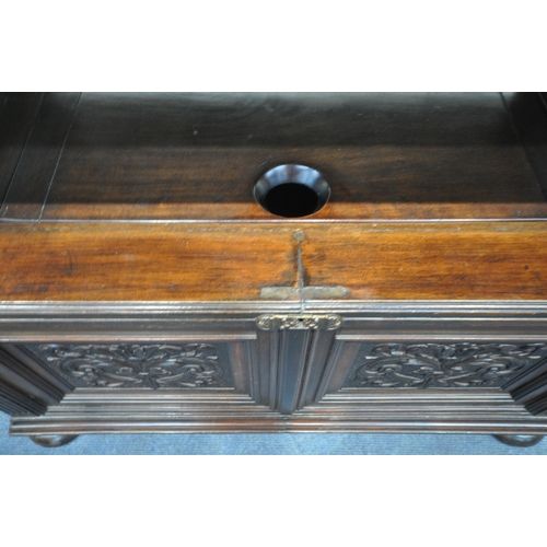 1315 - A 20TH CENTURY MAHOGANY MONKS BENCH, the tilting backrest with carved foliate details, that rest on ... 