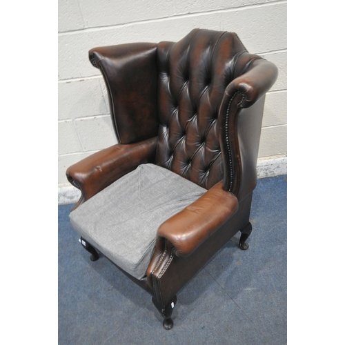 1319 - A BROWN LEATHER CHESTERFIELD WINGBACK ARMCHAIR, with buttoned back, later grey upholstered seat pads... 