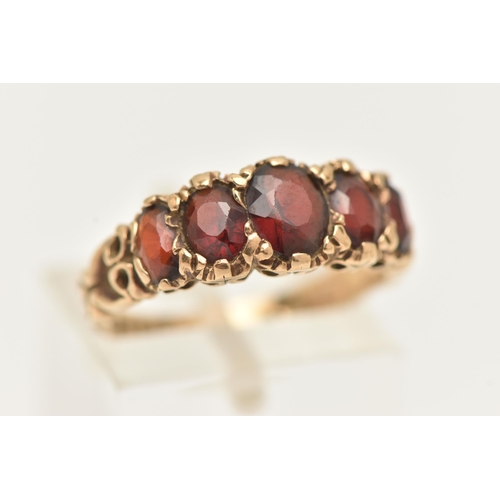 10 - A 9CT GOLD FIVE STONE GARNET RING, designed as a graduated line of five oval cut garnets with scroll... 