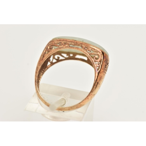 13 - A 9CT GOLD JADE RING, designed as an elongated oval jade panel within a collet setting to the scroll... 