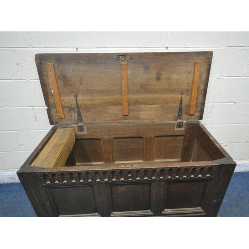 1230 - A GEORGIAN AND LATER OAK COFFER, the hinged lid enclosing a candle box, geometric carving to front a... 