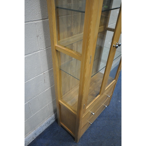 1286 - A MODERN OAK DISPLAY CABINET, the double doors enclosing two glass shelves, above two drawers, width... 