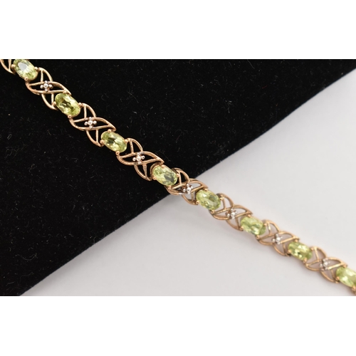 20 - A 9CT GOLD PERIDOT LINE BRACELET, designed as a series of seventeen oval cut peridots, each in a fou... 