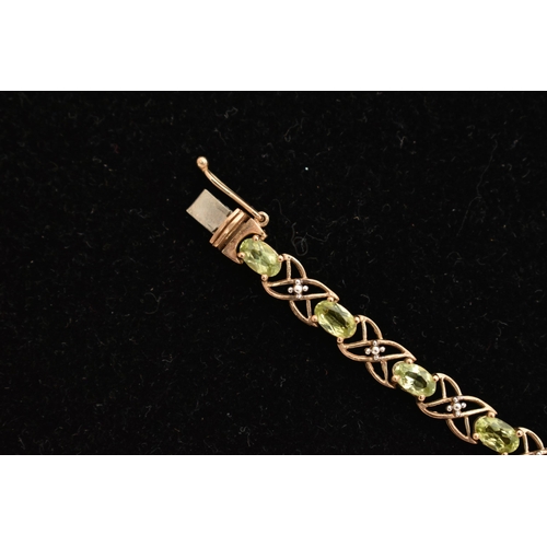 20 - A 9CT GOLD PERIDOT LINE BRACELET, designed as a series of seventeen oval cut peridots, each in a fou... 