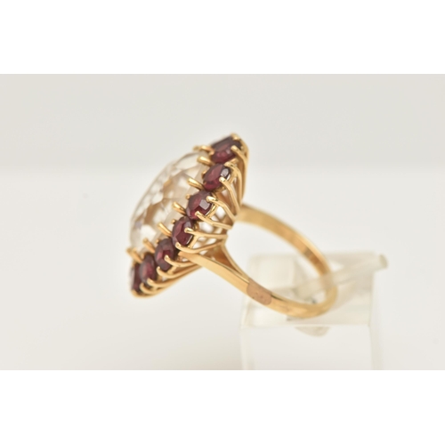 34 - A YELLOW METAL ROCK CRYSTAL AND GARNET CLUSTER RING, set with an oval shape rock crystal, measuring ... 