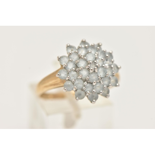 7 - A 9CT GOLD CLUSTER RING, large circular cluster set with circular cut light blue stones, each claw s... 