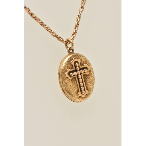 75 - A YELLOW METAL OVAL LOCKET WITH CHAIN, the oval hinged locket displaying a beaded cross to the front... 