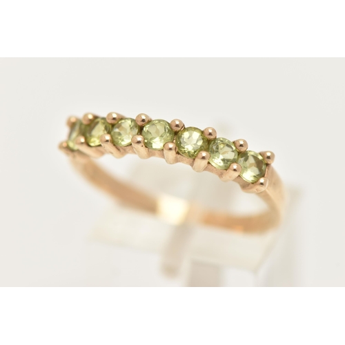 8 - A 9CT GOLD SEVEN STONE RING, set with seven circular cut green stones believed to be peridot, each i... 