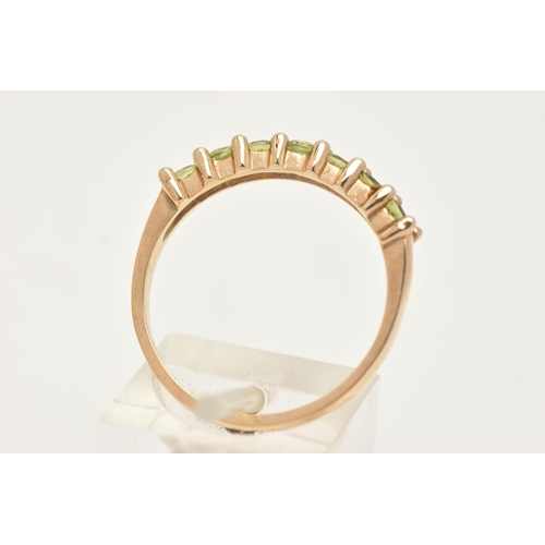 8 - A 9CT GOLD SEVEN STONE RING, set with seven circular cut green stones believed to be peridot, each i... 