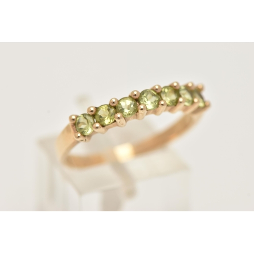 8 - A 9CT GOLD SEVEN STONE RING, set with seven circular cut green stones believed to be peridot, each i... 