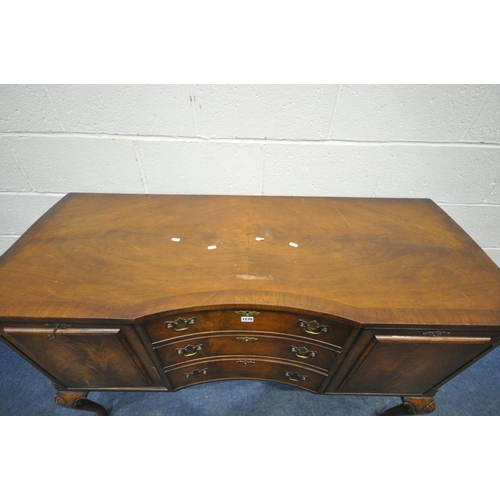 1197 - A 20TH CENTURY QUEEN ANNE STYLE CONCAVE WALNUT SIDEBOARD, fitted two cupboard doors, flanking three ... 