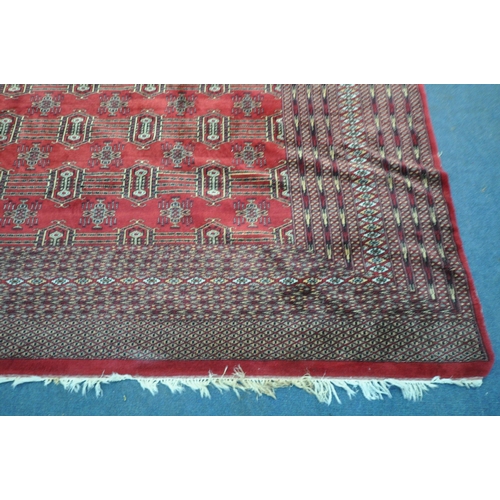 1320 - A LARGE MID TO LATE 20TH CENTURY WOOLLEN RUG, the repeating pattern surrounded by a multi strap bord... 