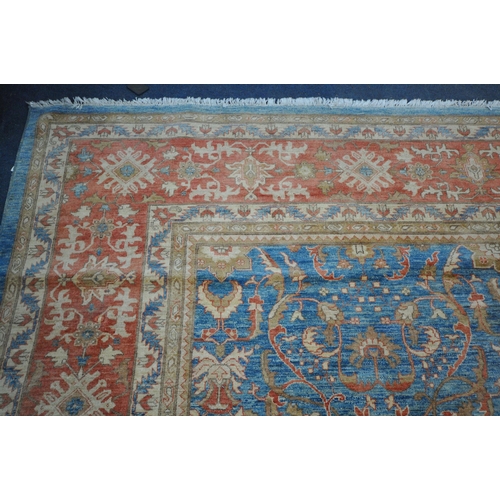 1321 - A LARGE MID TO LATE 20TH CENTURY WOOLLEN RUG, the repeating foliate pattern, within blue and orange ... 