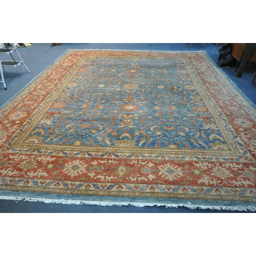 1321 - A LARGE MID TO LATE 20TH CENTURY WOOLLEN RUG, the repeating foliate pattern, within blue and orange ... 