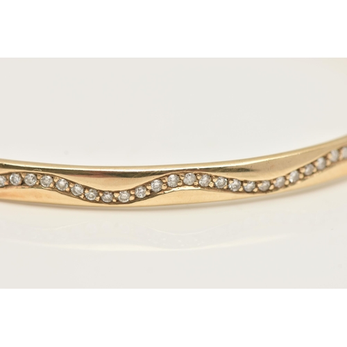 49 - A 9CT GOLD DIAMOND SET HINGED BANGLE, of a polished design, set with a wavy row of small round brill... 