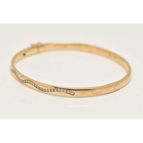 49 - A 9CT GOLD DIAMOND SET HINGED BANGLE, of a polished design, set with a wavy row of small round brill... 